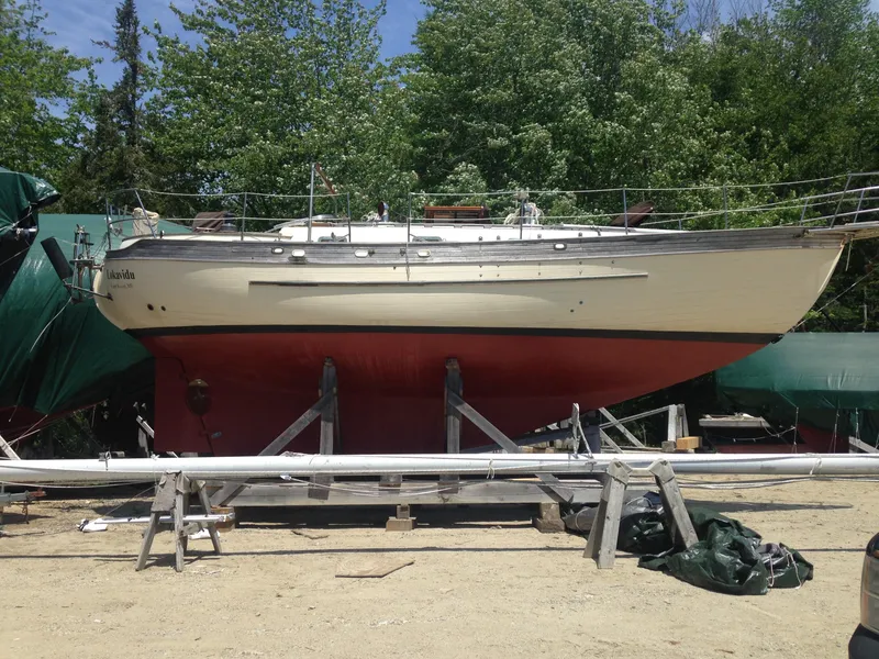 Slide: The Image of 1982 Young Sun Cutter sailboat on dry dock, surrounded by trees and equipment. - 49