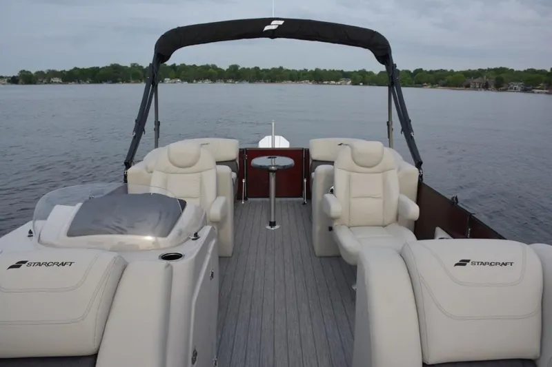 Slide: The Image of 2023 Starcraft SLS 1 pontoon boat with spacious seating and canopy on a lake. - 6