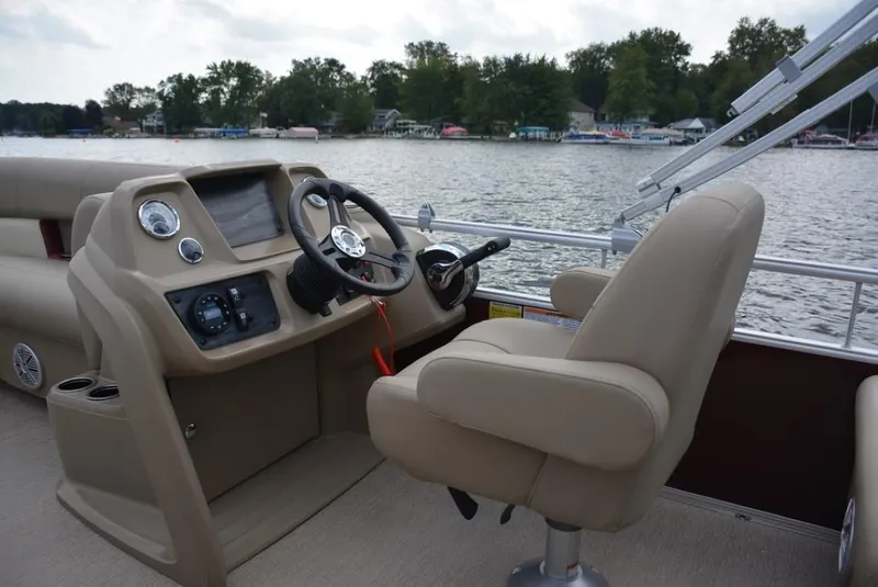 Slide: The Image of 2023 Starcraft LX 22 boat interior with steering console and captain's chair on a lake. - 13