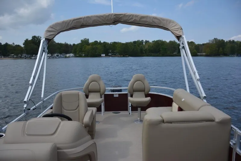 Slide: The Image of 2023 Starcraft LX 18 pontoon boat with beige seating on a lake. - 5