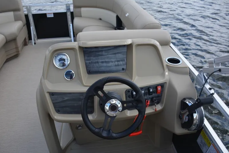 Slide: The Image of 2023 Starcraft LX 16 boat dashboard with steering wheel and controls on water. - 6