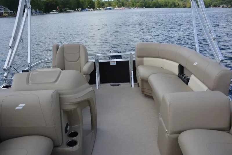 Slide: The Image of 2023 Starcraft LX 16 pontoon boat interior with beige seating on a lake. - 9