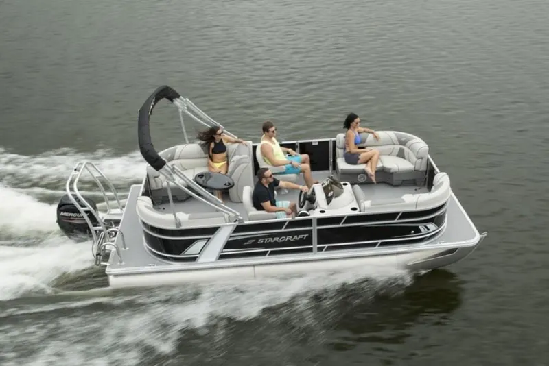 Slide: The Image of 2023 Starcraft EX 18 pontoon boat cruising on a lake with passengers. - 2