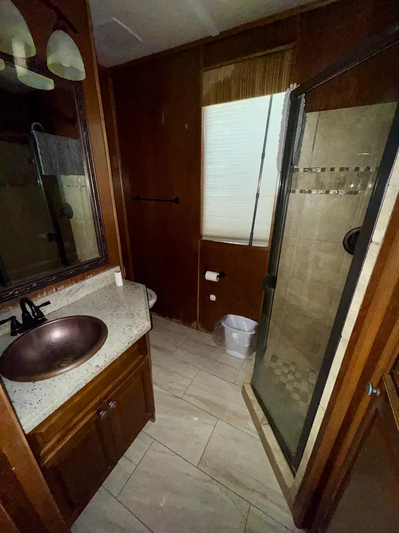 Slide: The Image of 2011 Bravada Dreamweaver Trip #16 bathroom with glass shower and wooden cabinetry. - 16
