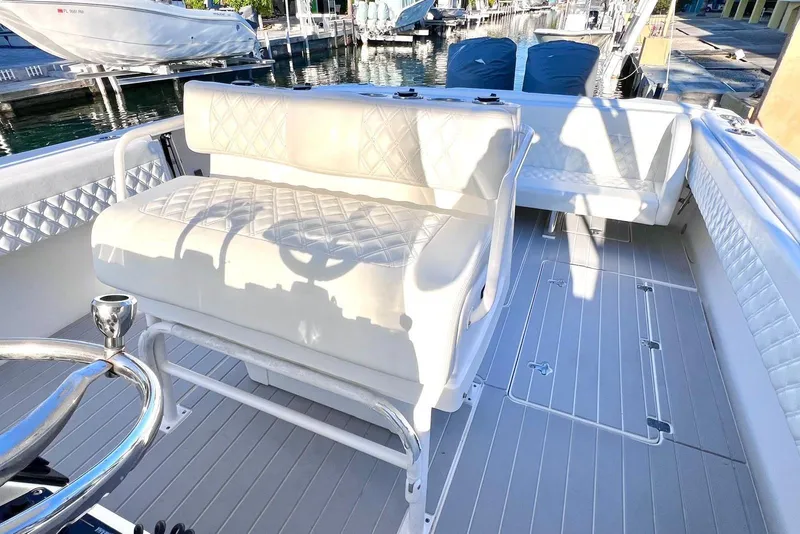 Slide: The Image of 2002 Intrepid 366 boat interior with white seating and steering wheel, docked by the water. - 15