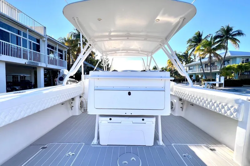 Slide: The Image of 2002 Intrepid 366 boat interior with white seating, docked near palm trees and waterfront homes. - 6