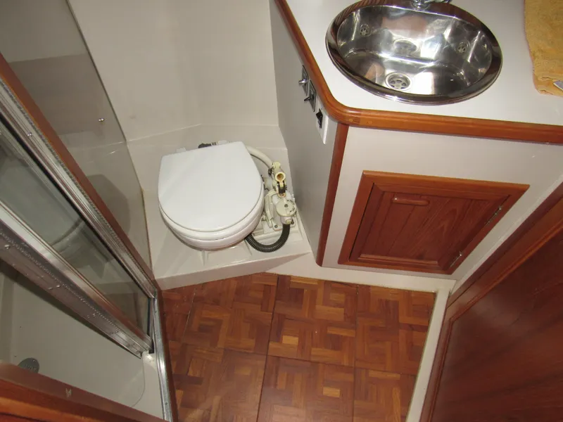 Slide: The Image of 1991 Carver 430 Cockpit Motor Yacht bathroom with toilet, sink, and wooden cabinetry. - 12