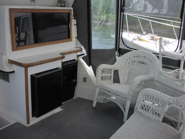 Slide: The Image of 1991 Carver 430 Cockpit Motor Yacht interior with wicker chairs and compact kitchenette. - 13