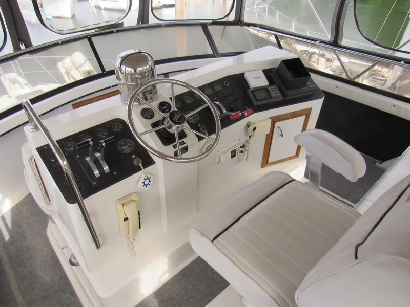 Slide: The Image of 1991 Carver 430 Cockpit Motor Yacht helm with steering wheel, controls, and seating. - 16