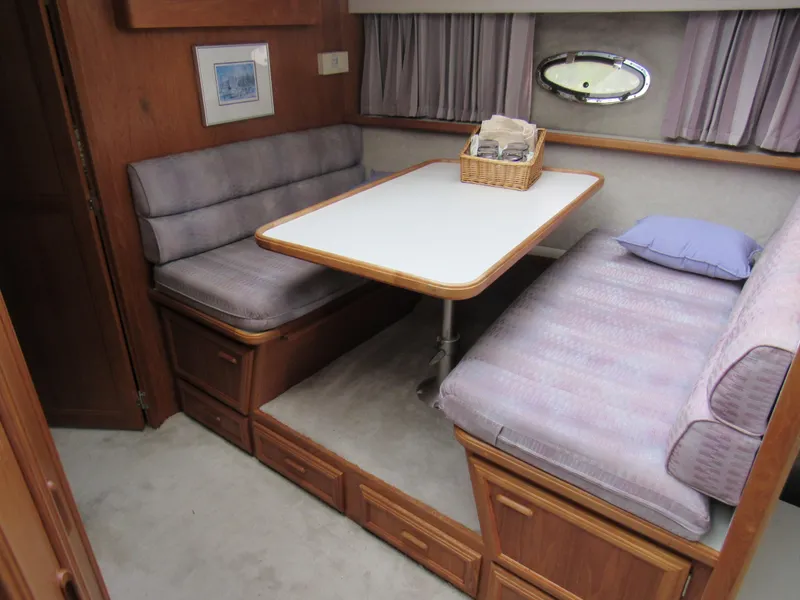 Slide: The Image of 1991 Carver 430 Cockpit Motor Yacht interior with dining area, cushioned seating, and wooden cabinetry. - 8