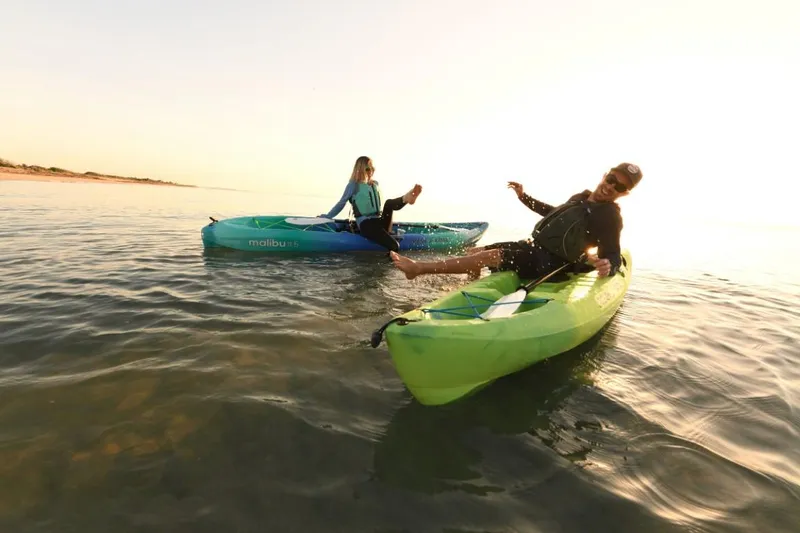 Slide: The Image of Two people kayaking on Ocean Kayak Malibu 11.5, 2023 model, in calm waters at sunset. - 13
