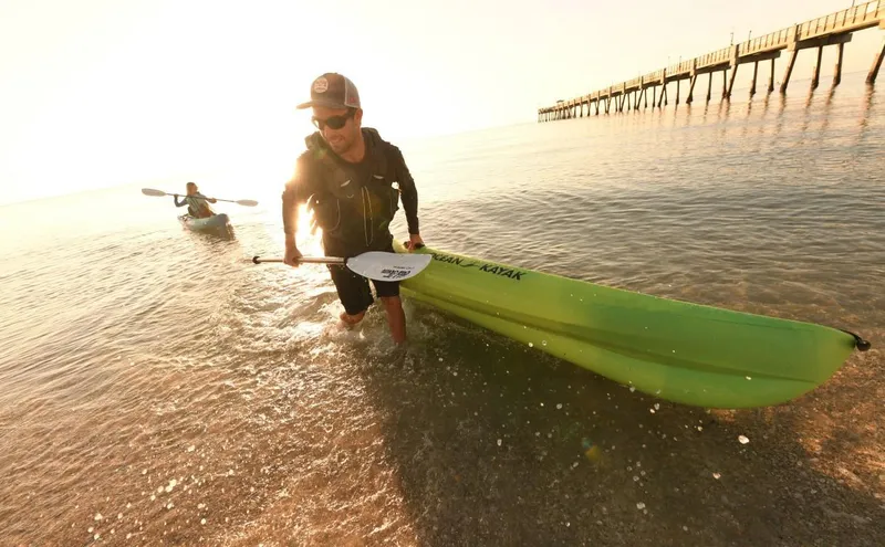 Slide: The Image of Two people kayaking with Ocean Kayak Malibu 11.5, 2023 model, near a pier at sunset. - 28