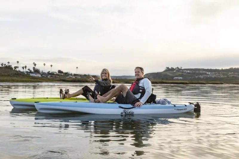 The Image of Two people kayaking on Hobie Passport 10.5 kayaks, 2023 model, in a serene water setting. - 0