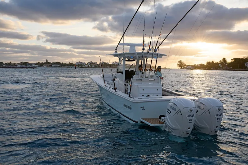 Slide: The Image of 2025 Regulator 31 boat cruising at sunset with fishing rods and twin Yamaha engines. - 10