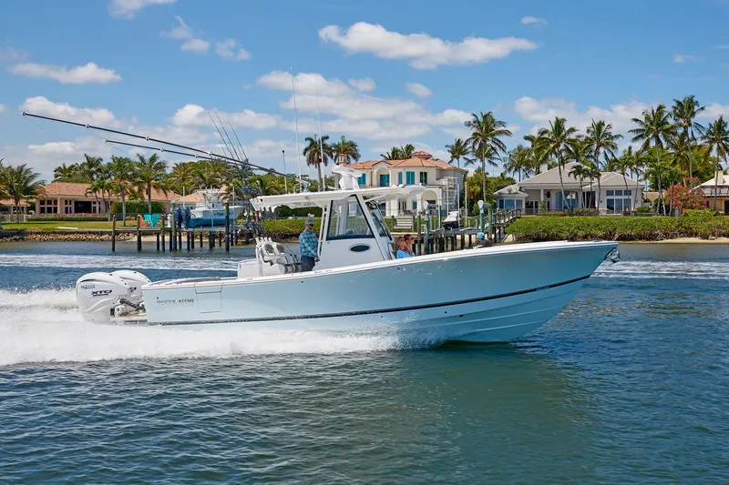 Slide: The Image of 2025 Regulator 31 boat cruising on water near waterfront homes and palm trees. - 5