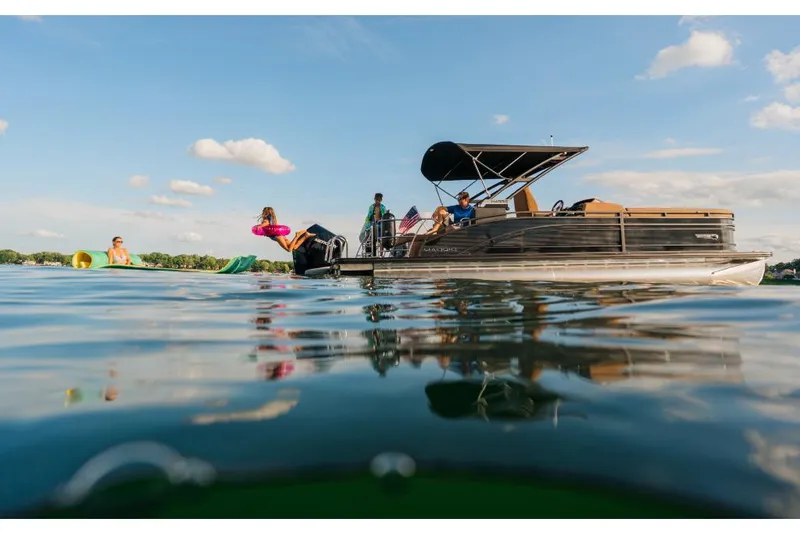 Slide: The Image of 2023 Harris Solstice 250 pontoon boat on a sunny lake with people enjoying water activities. - 2