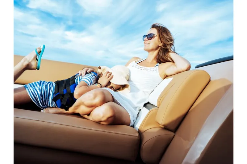 Slide: The Image of Woman and child relaxing on a 2023 Harris Solstice 250 boat under a blue sky. - 24