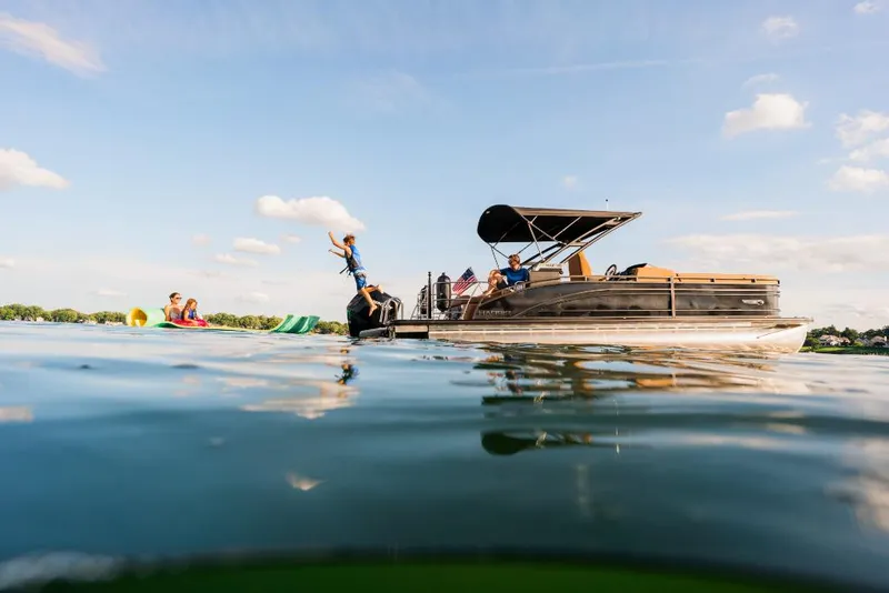Slide: The Image of 2023 Harris Solstice 250 pontoon boat on a lake with people enjoying water activities. - 3