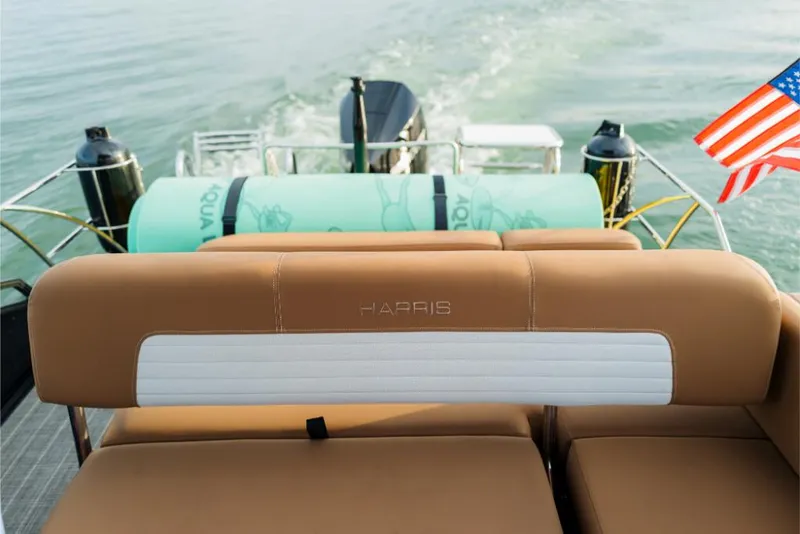 Slide: The Image of 2023 Harris Solstice 250 boat with tan seating and American flag on water. - 8