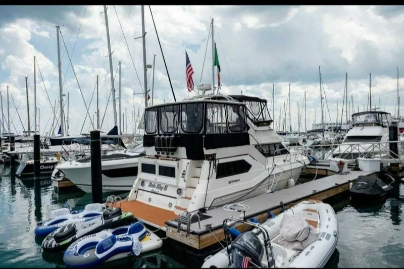 Slide: The Image of 1991 Cruisers Yachts 3850 Aft Cabin docked at marina with inflatables nearby. - 3