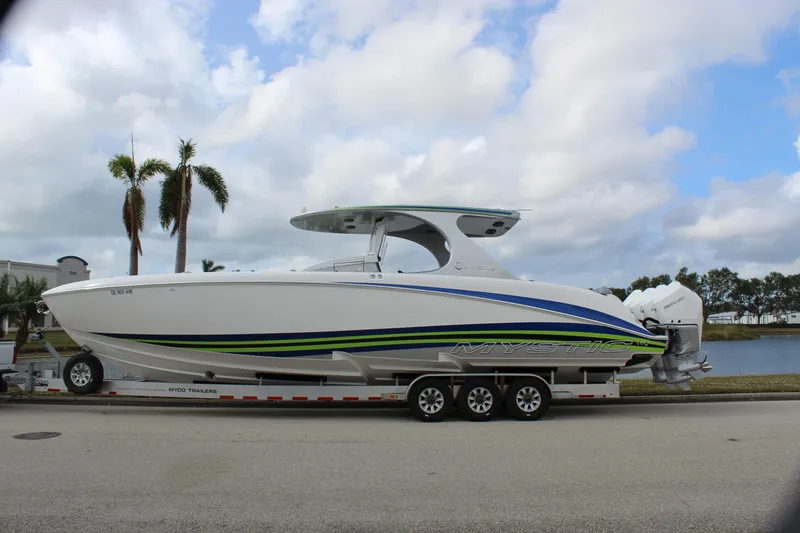 Slide: The Image of 2020 Mystic Powerboats M4200 on trailer, sleek design, vibrant stripes, parked by waterfront. - 3
