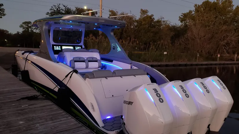 Slide: The Image of 2020 Mystic Powerboats M4200 with illuminated interior and four Mercury engines docked at sunset. - 66