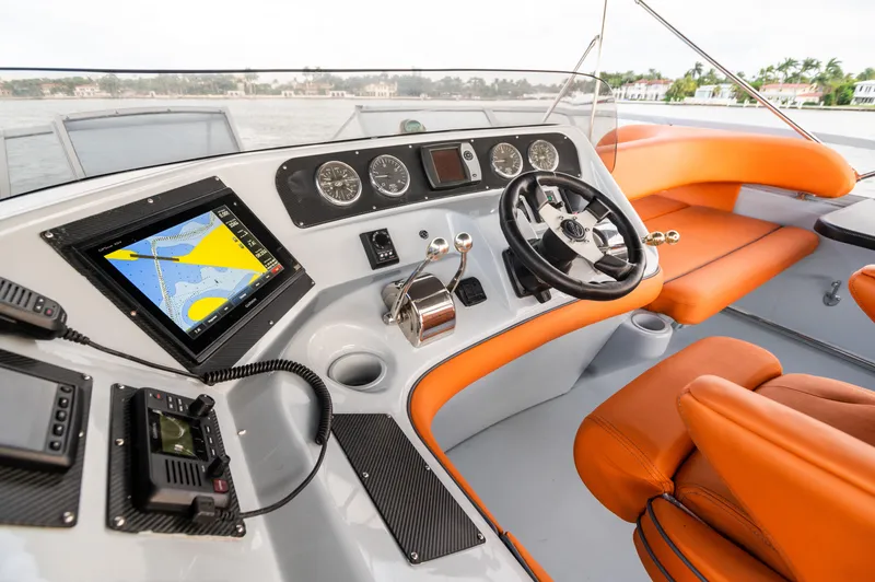 Slide: The Image of 2003 Sea Ray Express Bridge helm with orange seating, navigation system, and steering wheel. - 7