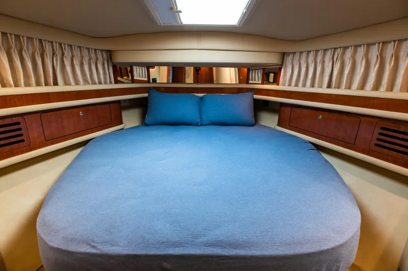 Slide: The Image of 2003 Sea Ray Express Bridge cabin with a cozy bed and elegant wood accents. - 8