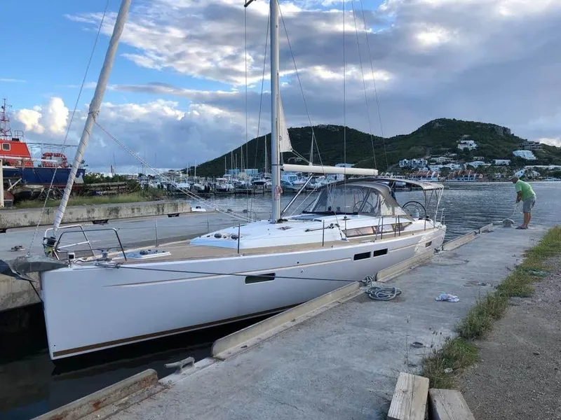 Slide: The Image of 2015 Jeanneau Sun Odyssey 469 sailboat docked at a marina with scenic hills. - 15