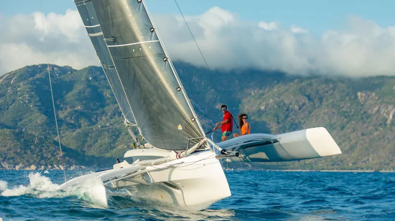 The Image of Sailing Corsair 880 catamaran on blue ocean with mountainous backdrop, 2025 model. - 0