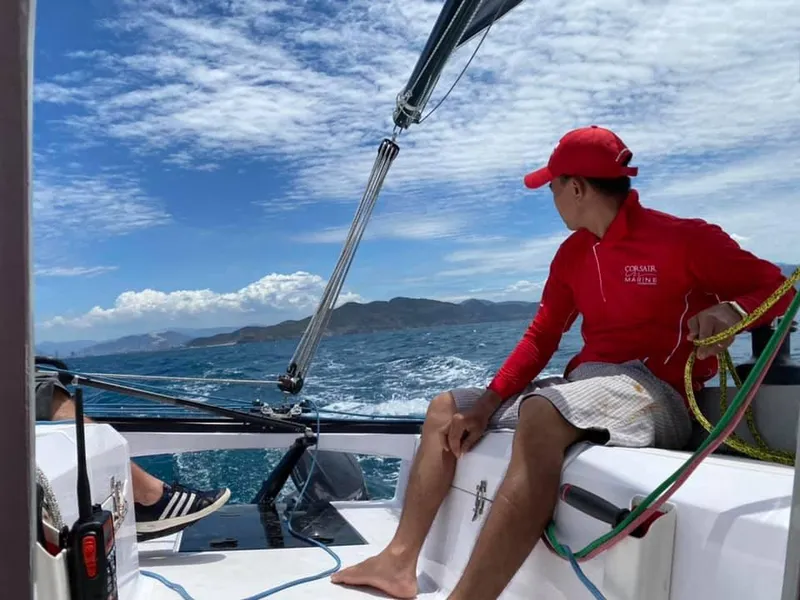 Slide: The Image of Man sailing Corsair 880 boat on open sea, wearing red jacket and cap, 2025 model. - 10