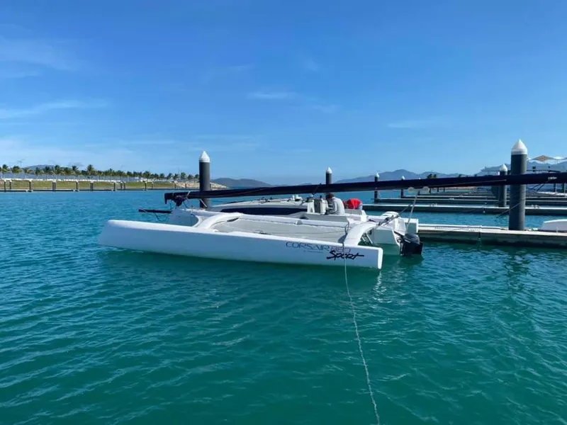 Slide: The Image of 2025 Corsair 880 trimaran docked in a serene marina under a clear blue sky. - 14
