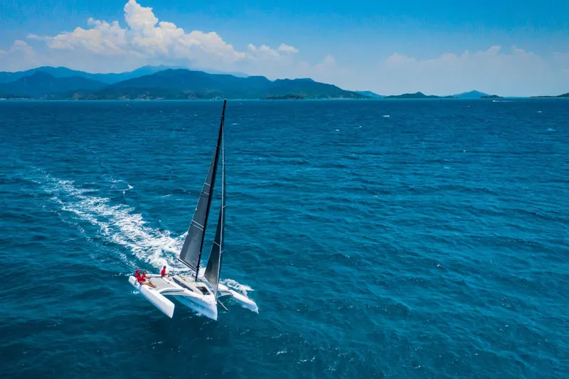 Slide: The Image of Sailing Corsair 880 trimaran on open sea, 2025 model, under clear blue sky. - 3