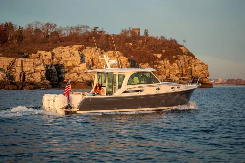 Slide: The Image of 2025 Back Cove 39O cruising near rocky coastline at sunset. - 6