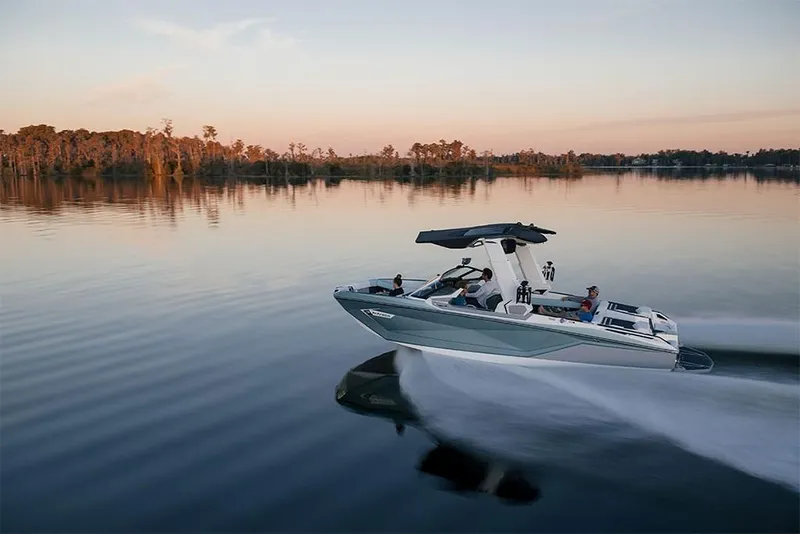 Slide: The Image of 2023 Nautique Super Air Nautique G25 Paragon cruising on a serene lake at sunset. - 10