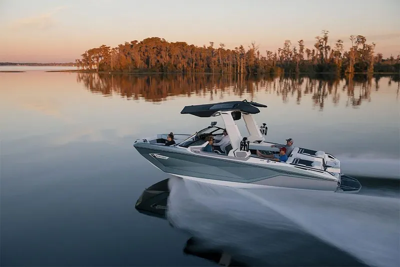 Slide: The Image of 2023 Nautique Super Air Nautique G25 Paragon cruising on a serene lake at sunset. - 2