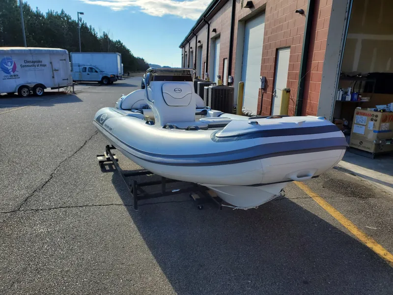 Slide: The Image of 2025 Walker Bay Venture inflatable boat parked outside a warehouse. - 13