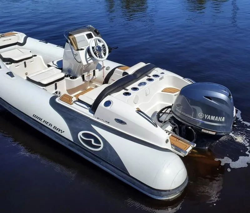 Slide: The Image of 2025 Walker Bay Venture boat with Yamaha outboard motor on calm water. - 2
