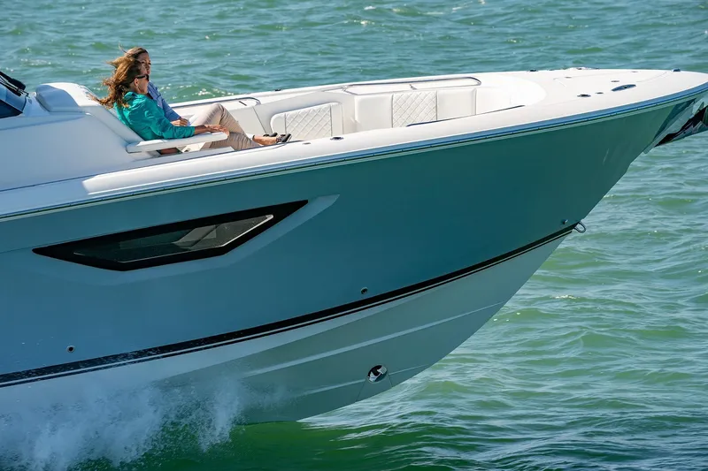 Slide: The Image of 2025 Pursuit S 378 boat cruising on water with a person relaxing on deck. - 3