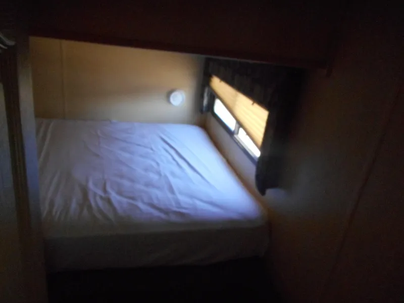 Slide: The Image of Small bedroom with a bed and window in a 2005 Twin Anchors Caspian #3 houseboat. - 19