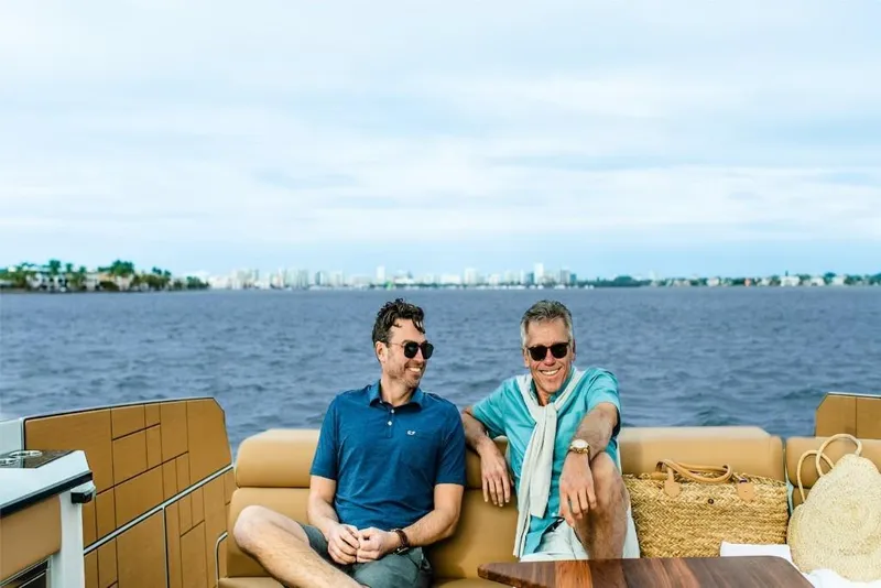 Slide: The Image of Two men relaxing on a 2023 Aviara AV40 boat with city skyline in background. - 11