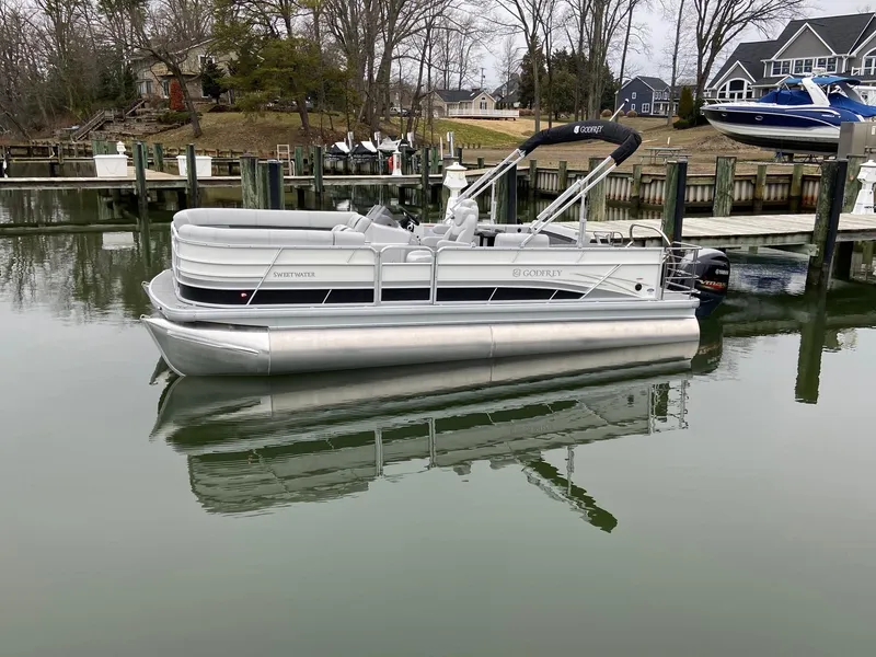 Slide: The Image of 2020 Sweetwater 2286 SFL pontoon boat docked in a calm marina. - 2