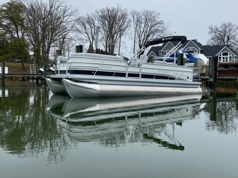 Slide: The Image of 2020 Sweetwater 2286 SFL pontoon boat on calm water near dockside homes. - 3
