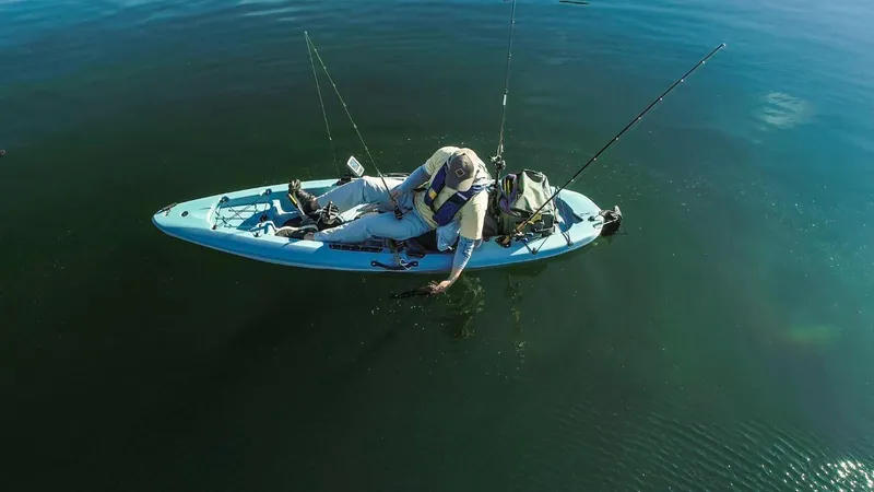 Slide: The Image of Person fishing on a 2023 Hobie MIRAGE PASSPORT 10.5 kayak in calm waters. - 2