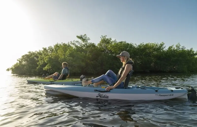 Slide: The Image of Two people kayaking on Hobie MIRAGE PASSPORT 10.5 kayaks, 2023 model, near lush greenery. - 3