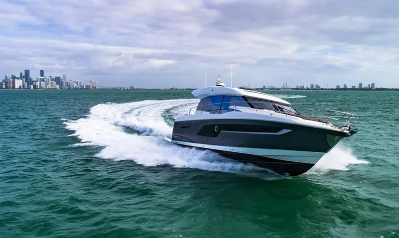 Slide: The Image of 2024 Prestige 520 S yacht cruising on open water with city skyline in background. - 10