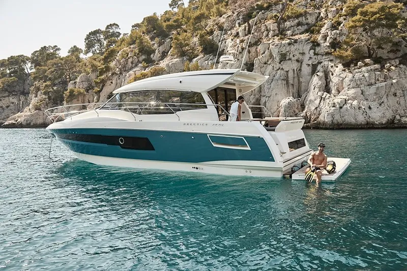 Slide: The Image of 2023 Prestige 460 S yacht anchored near rocky coastline with people enjoying the water. - 11