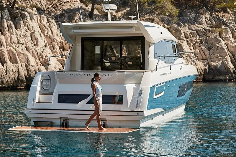 Slide: The Image of 2023 Prestige 460 S yacht anchored near rocky shore with a person on the swim platform. - 12