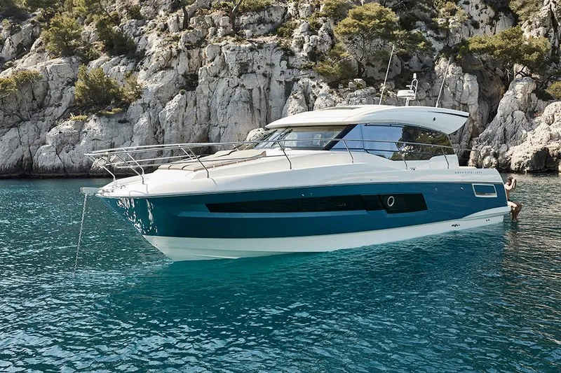Slide: The Image of 2023 Prestige 460 S yacht anchored in clear blue water near rocky cliffs. - 14