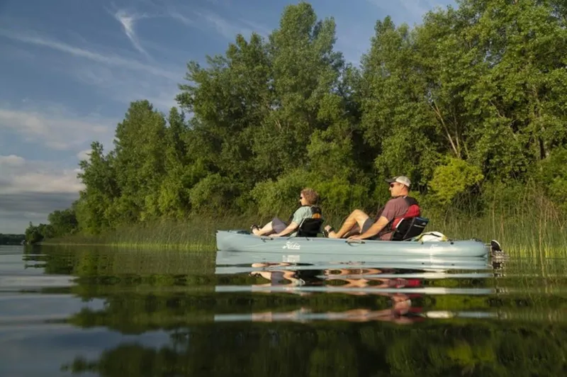 Slide: The Image of Two people kayaking on a 2023 Hobie Mirage Oasis in a serene lake. - 3